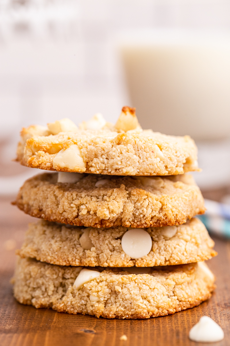 Stack of four Keto White Chocolate Macadamia COokies on a wooden table.