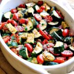 Italian baked zucchini and tomatoes in a white casserole dish.