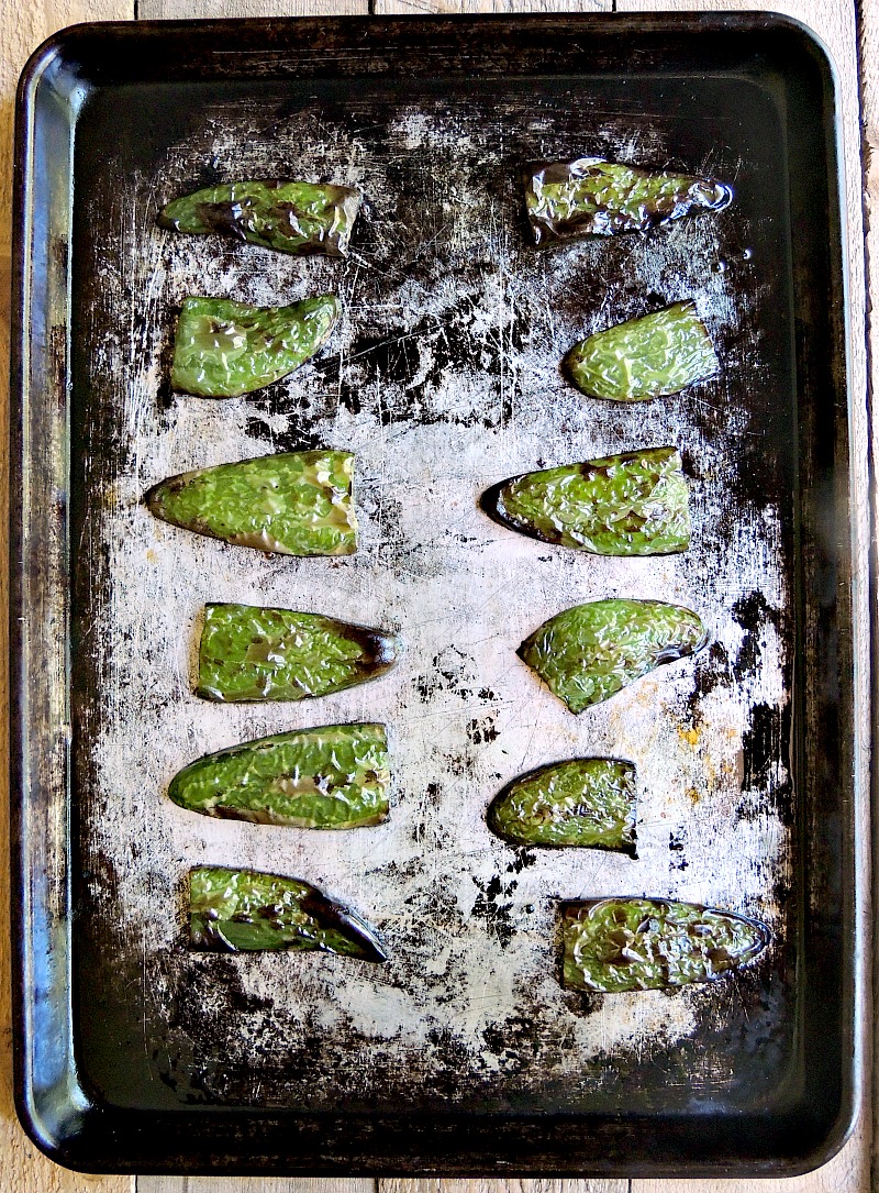 Overhead view of roasted jalapenos halves right out of the oven on an old baking sheet.