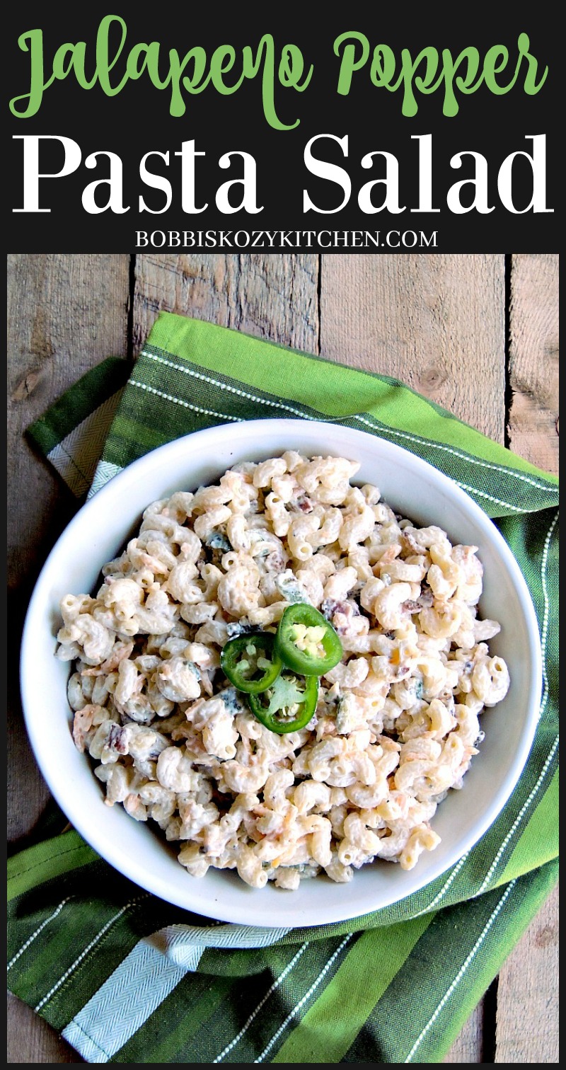 Overhead view of a bowl of jalapeno popper pasta salad on a wooden table with a green striped kitchen towel.