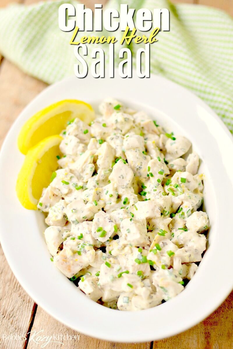 Lemon herb chicken salad in a white serving bowl with lemon wedges.