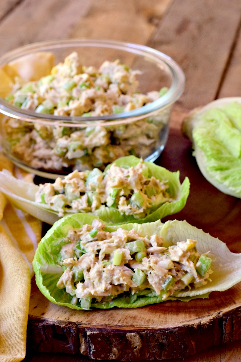 Two romaine lettuce cups with keto tuna salad in them on a round wooden cutting board.