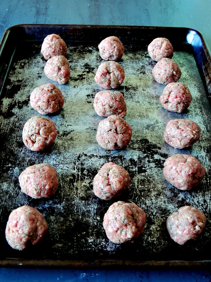 Uncooked gyro meatballs on a metal baking sheet.