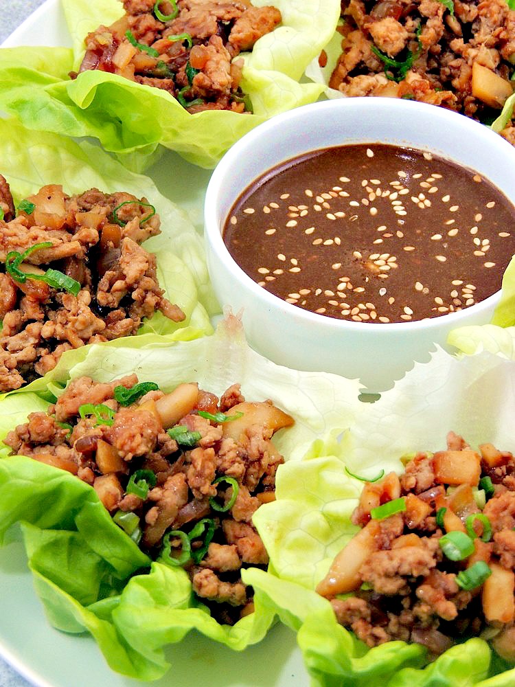 Copycat PF Chang’s Chicken Lettuce Wraps on a white serving platter with dipping sauce in a white bowl.