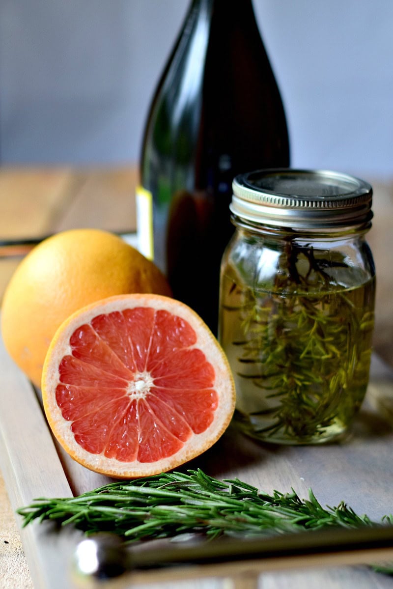 Ingredients for Rosemary Pink Grapefruit Mimosas on a wooden serving tray