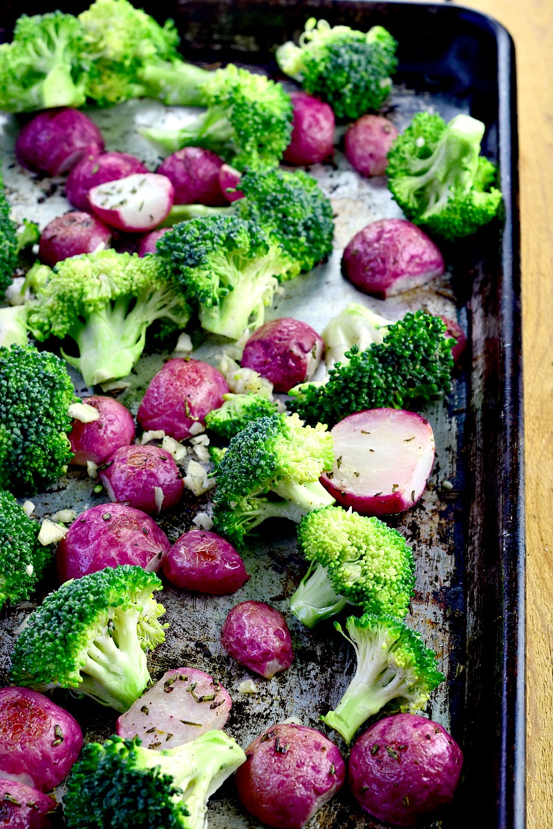 Broccoli florets with roasted radishes on a sheet pan.