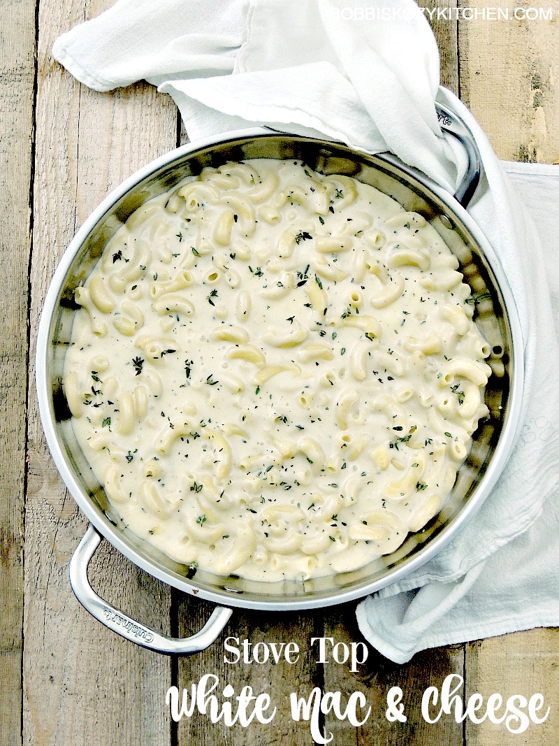 Overhead view of a silver pot full of keto stovetop white mac and cheese on a wooden table with a white kitchen towel underneath the pot.