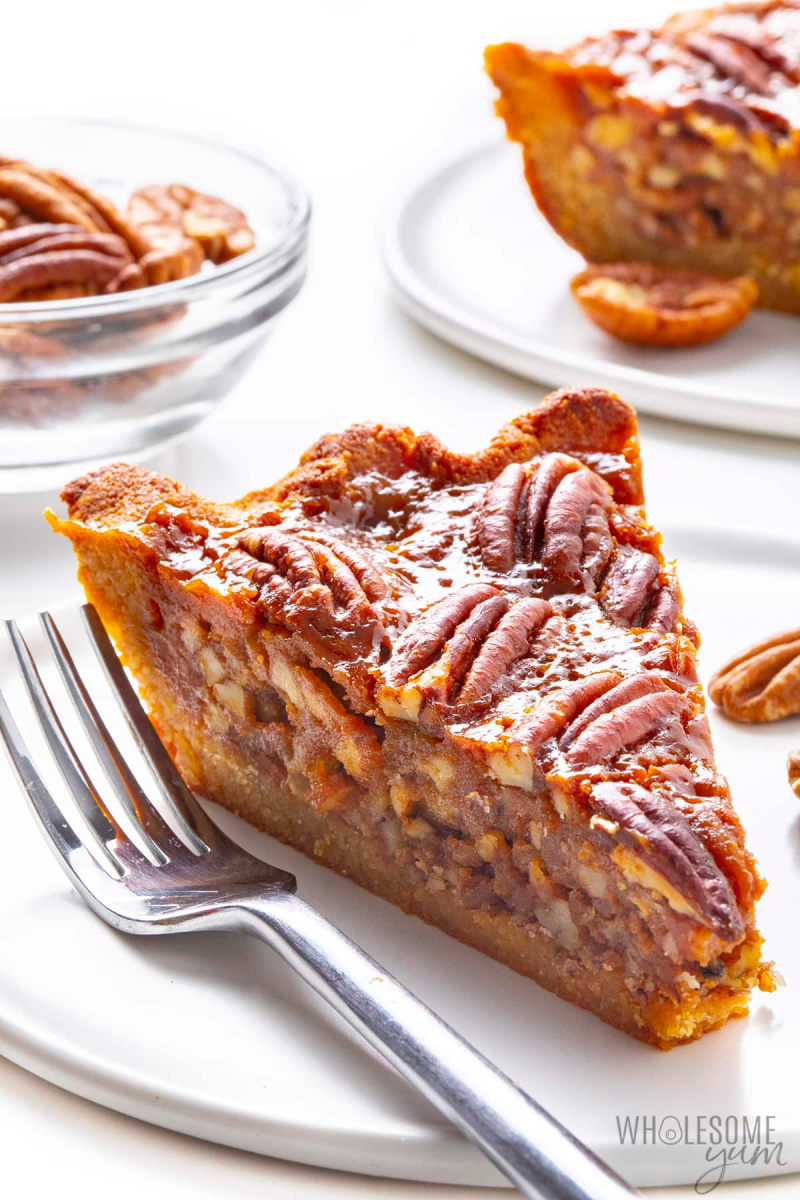 Photo of a piece of keto pecan pie on a white plate with a fork.
