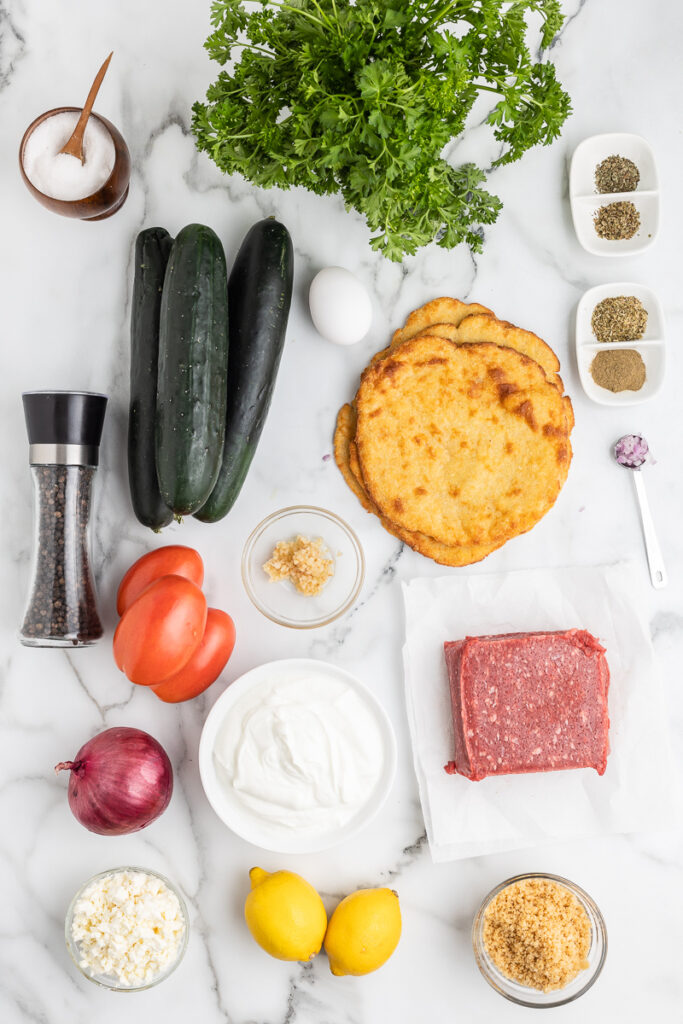 Overhead photo of the ingredients needed to make Low Carb Gyros on a white marble counter.