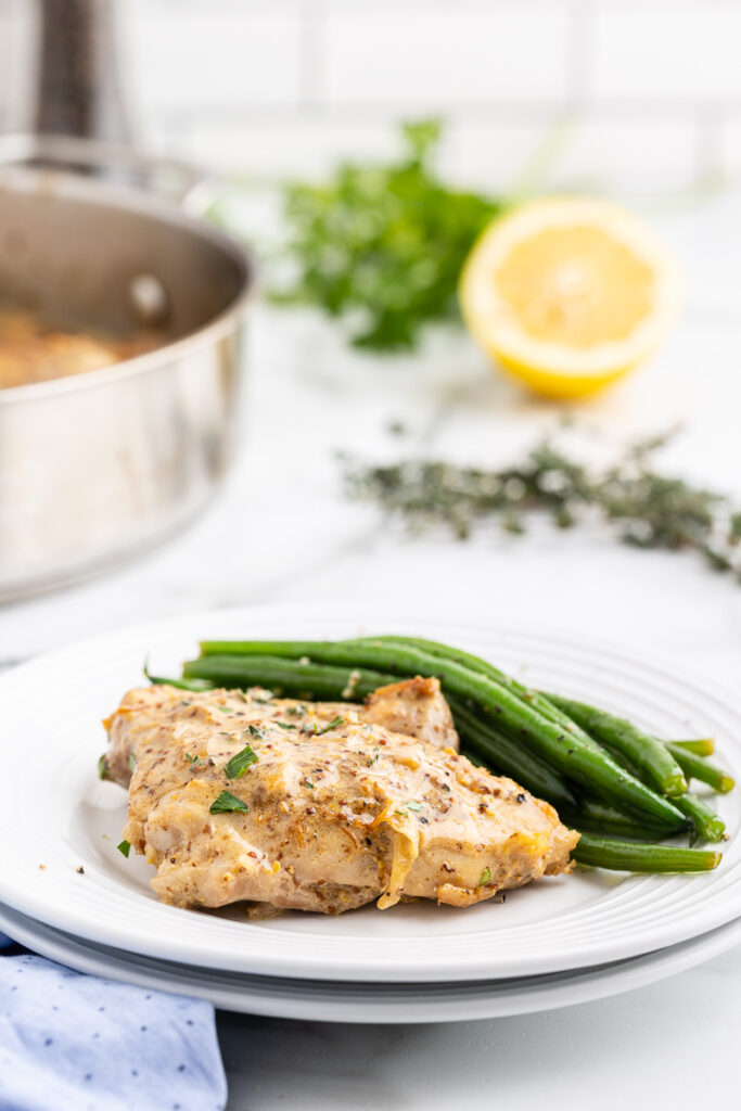 Creamy Mustard Chicken on a white plate with green beans.