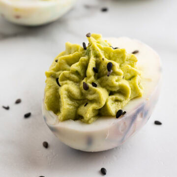 A closeup of a halloween deviled egg sitting on a white marble counter.
