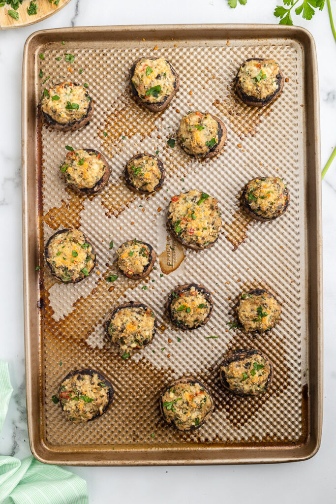 Overhead view of Keto Crab Stuffed Mushrooms just out of the oven on a bronze baking sheet.
