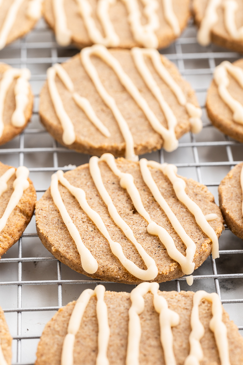 Image shows several keto chair sugar cookies with glaze drizzled across them on a metal cooling rack.