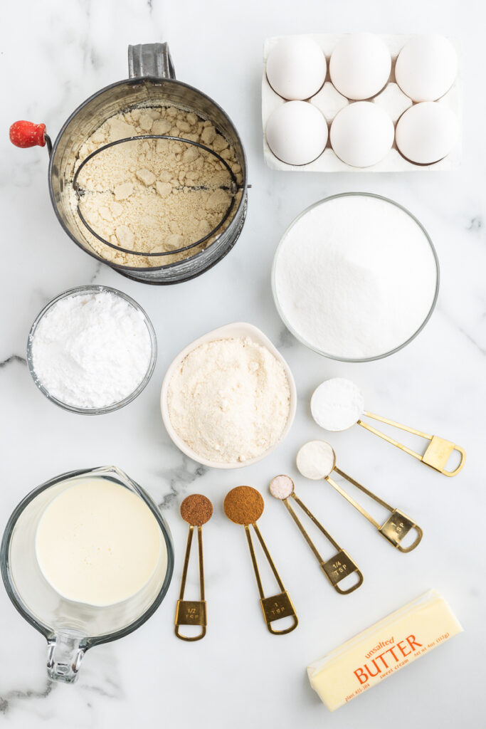 Overhead view of the ingredients needed to make Keto Eggnog Pound Cake on a white marble counter.