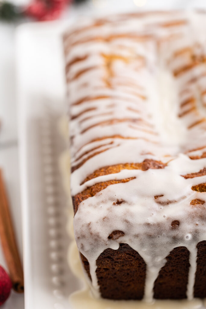 Closeup of Keto Eggnog Pound Cake drizzled with eggnog glaze on a white serving tray.
