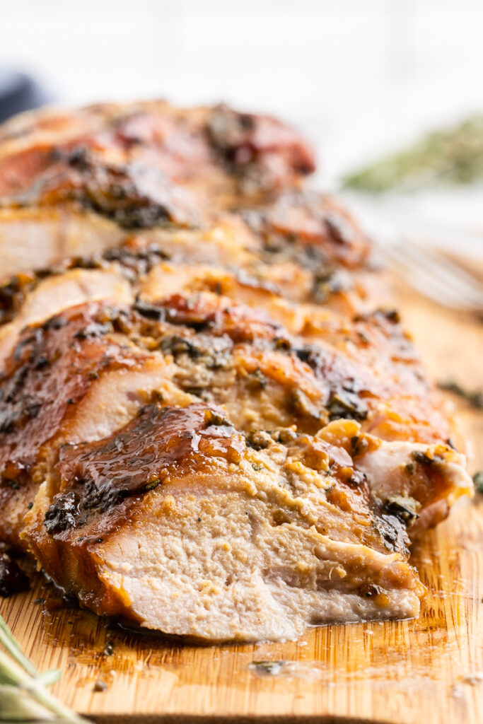 Keto Maple Mustard Roasted Turkey Breast sliced on a wooden cutting board.