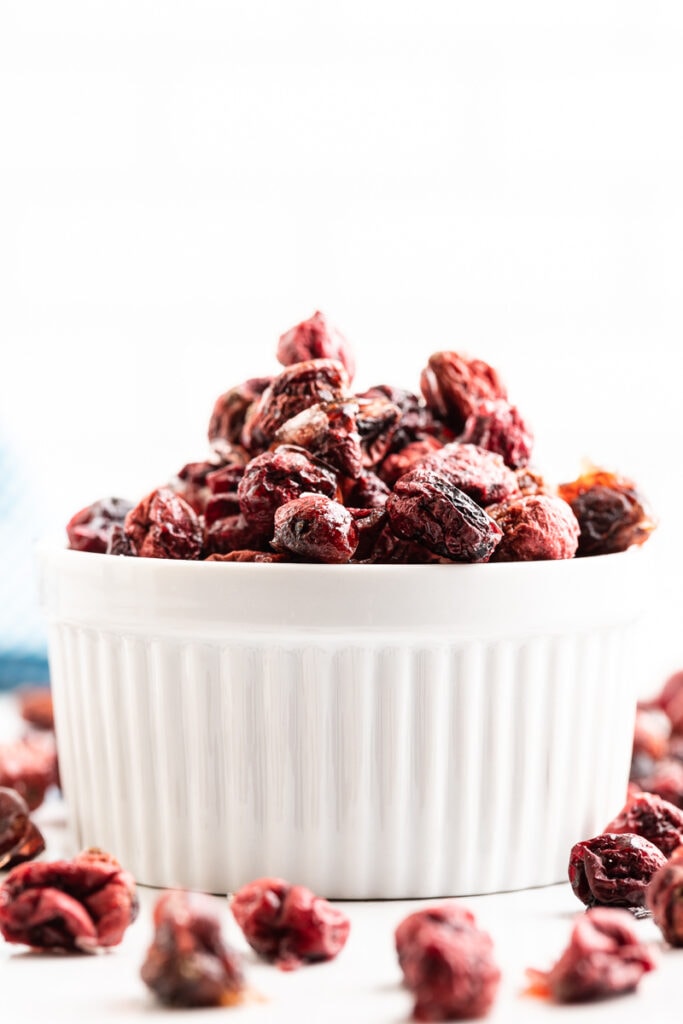 A white ramekin filled with sugar-free dried cranberries on a white counter.