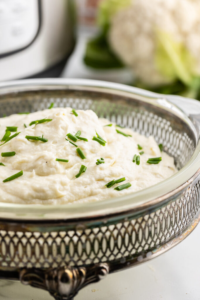 Close up of Creamy Garlic Mashed Cauliflower in a glass serving dish.