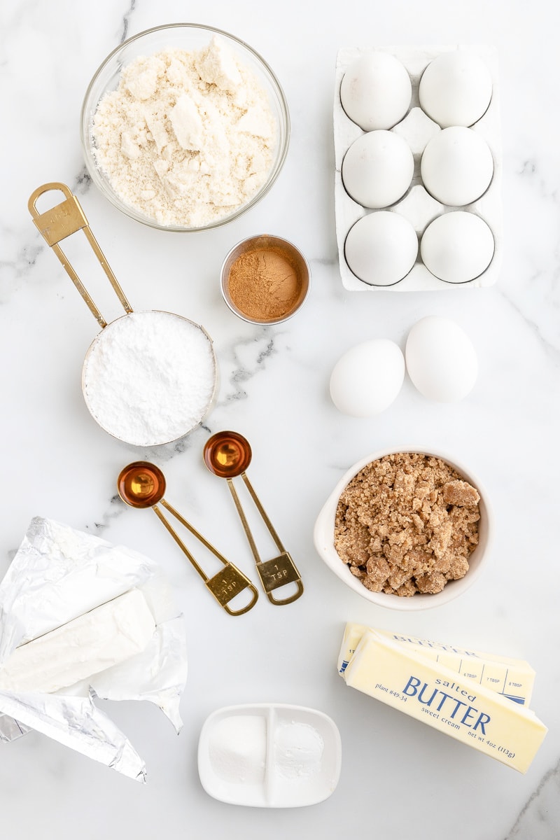 All of the ingredients needed to make keto cinnamon roll pancakes on a white marble counter.