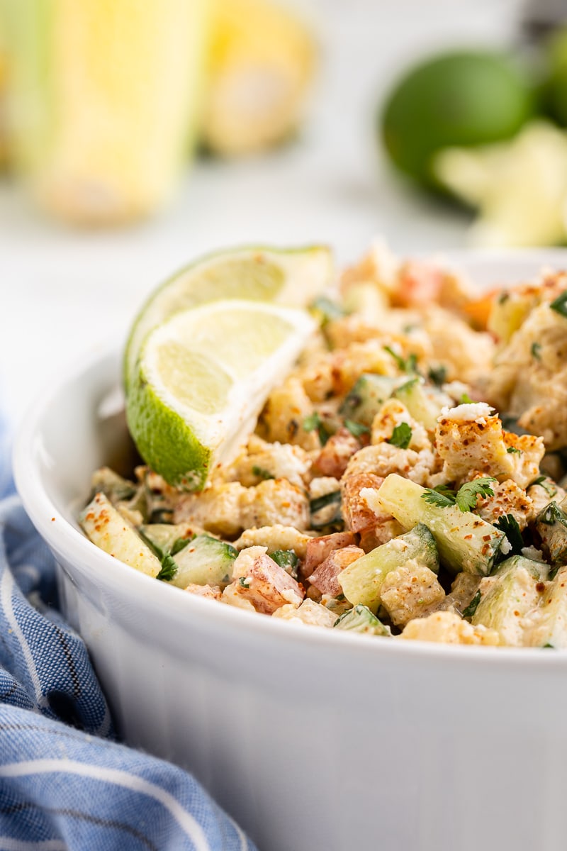 Low carb Mexican street corn in a white bowl with a lime wedge.