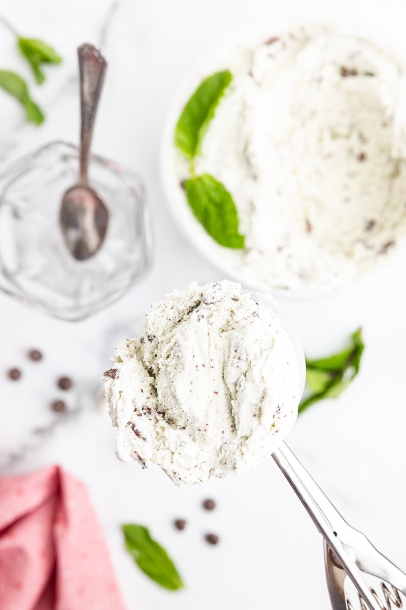 Overhead view of an ice cream scooper holding a scoop of keto mint chocolate chip ice cream.