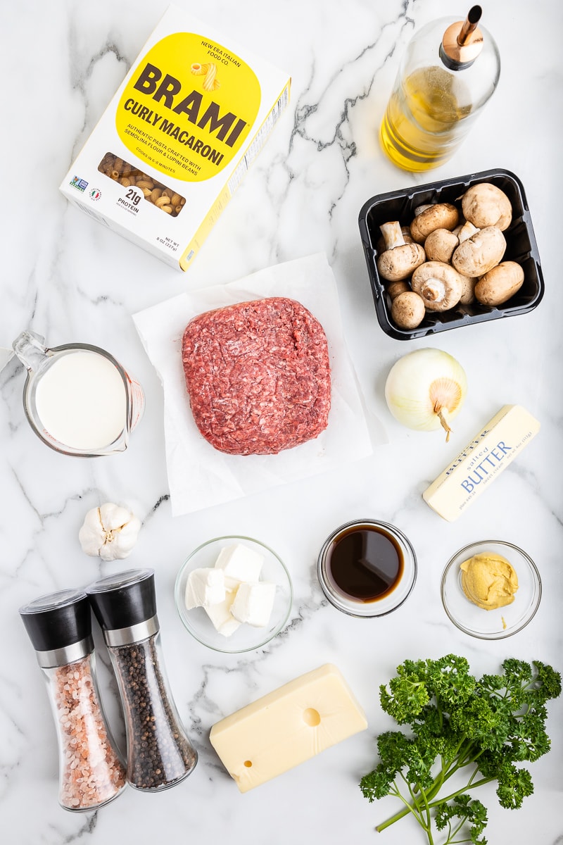 Photo of the ingredients needed to make Low Carb Mushroom Swiss Cheeseburger Pasta on a white marble counter.