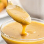 Keto honey mustard sauce in a small glass bowl with a silver spoon.