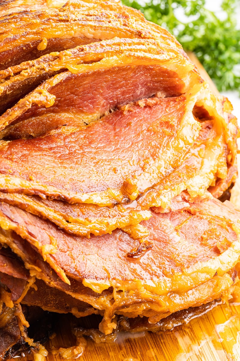 Close up of keto slow cooker maple mustard ham on a wooden cutting board.