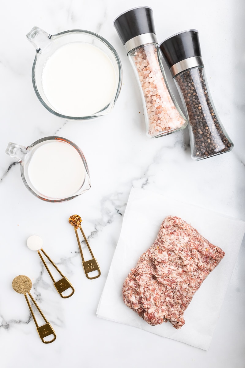 The ingredients needed to make keto sausage gravy on a white marble counter.