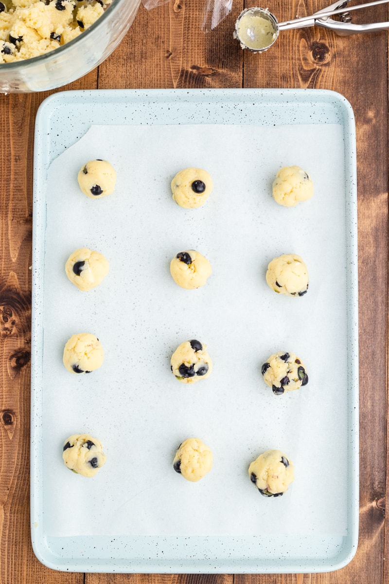 Balls of keto blueberry cheesecake cookie dough on a baking sheet, step 7.