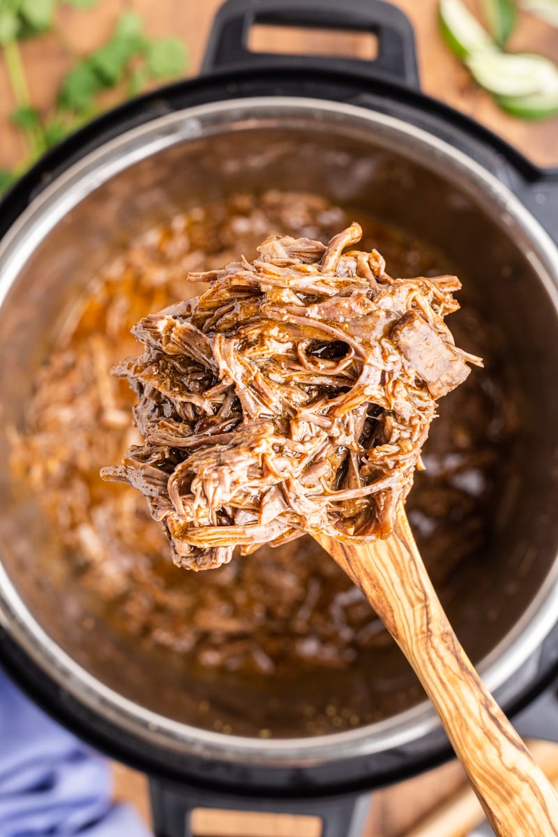 Combining the shredded beef with the sauce in the Instant Pot.