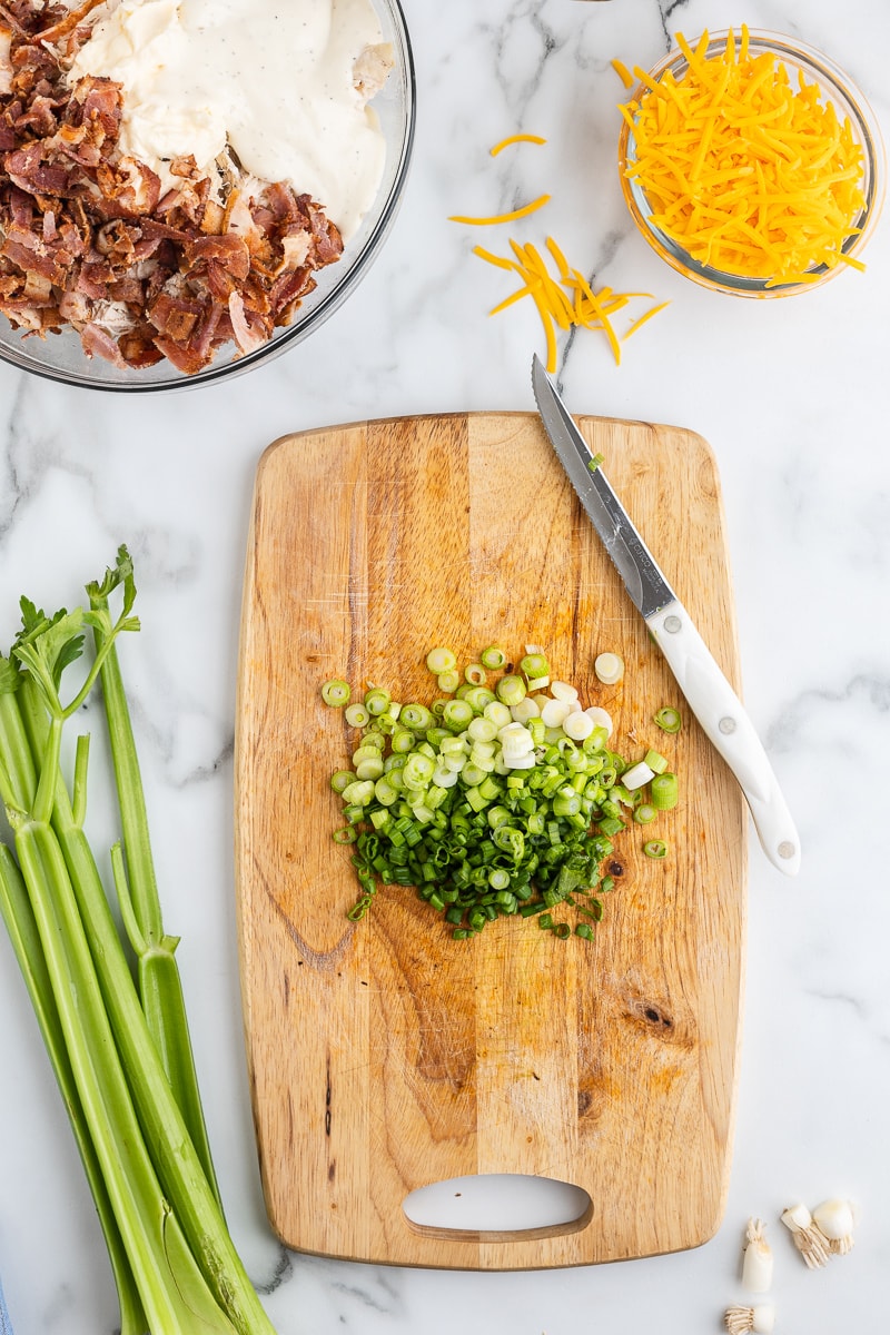 Chopped green onions on a wooden cutting board.