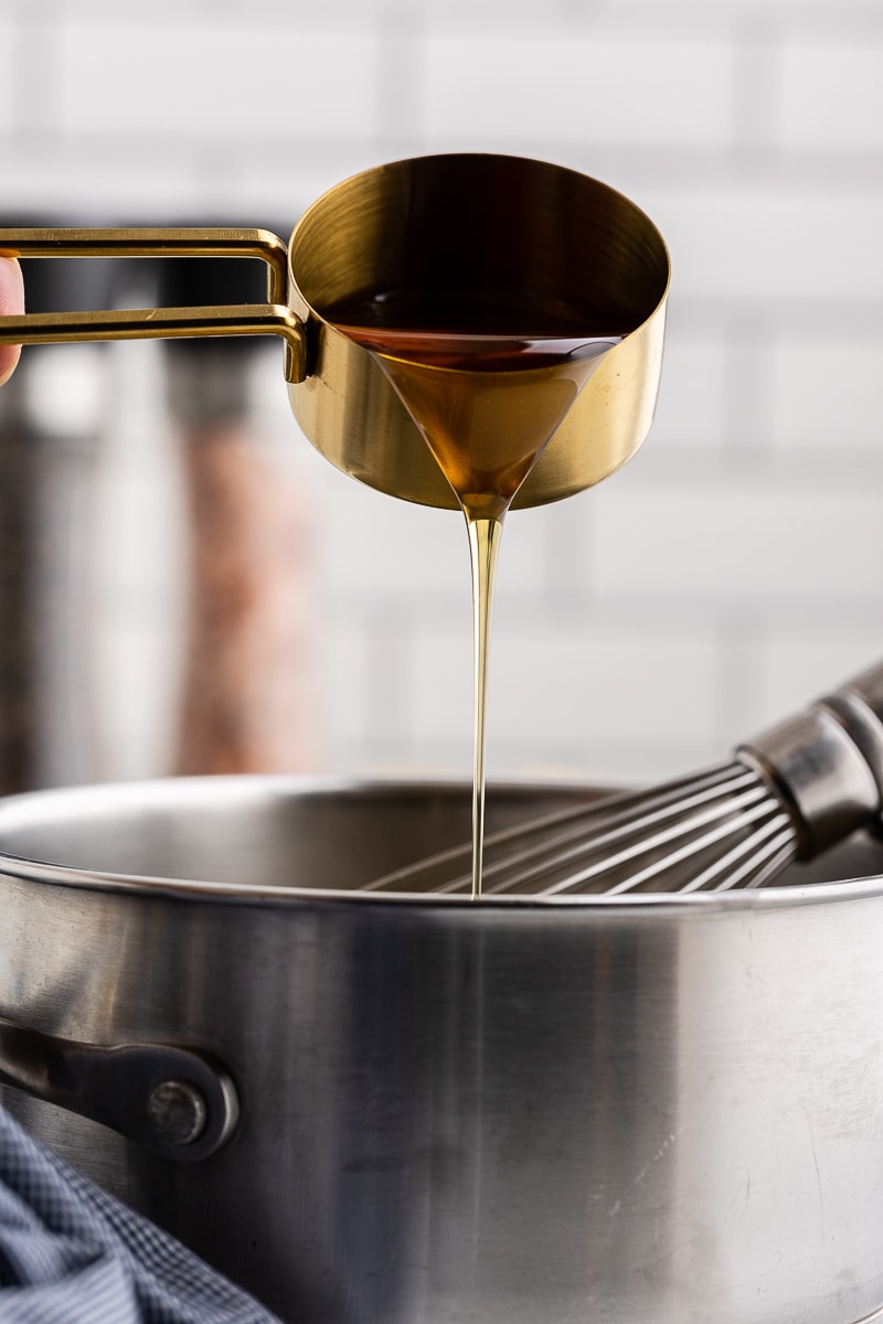 Honey being poured into a silver saucepot.
