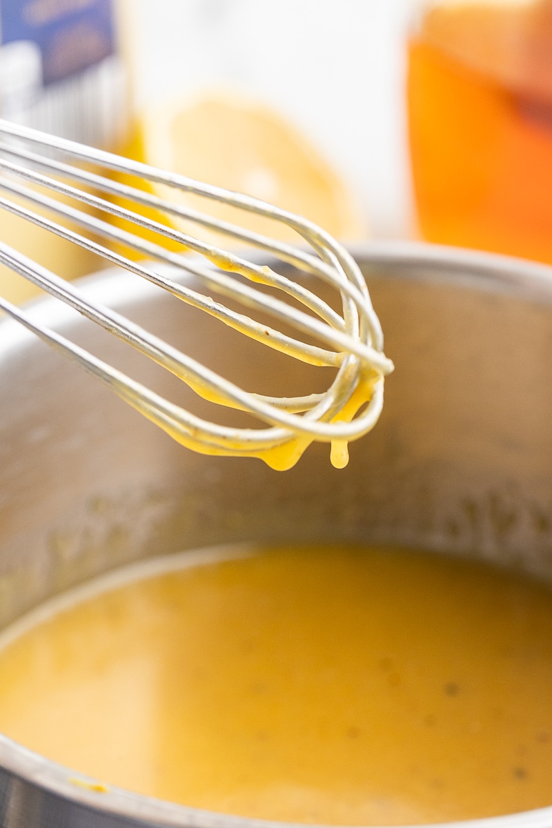 Keto honey mustard sauce in a saucepot with a whisk.