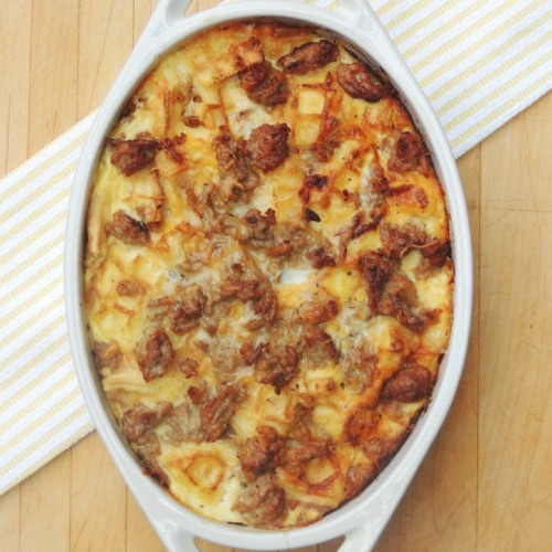 Overhead view of Make Ahead Waffle Casserole in a white baking dish on a wooden table.