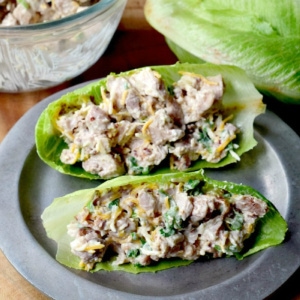 Two loaded chicken salad lettuce wraps on a metal plate.