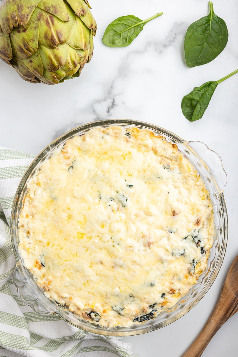 Baked keto spinach artichoke dip in a glass pie pan.