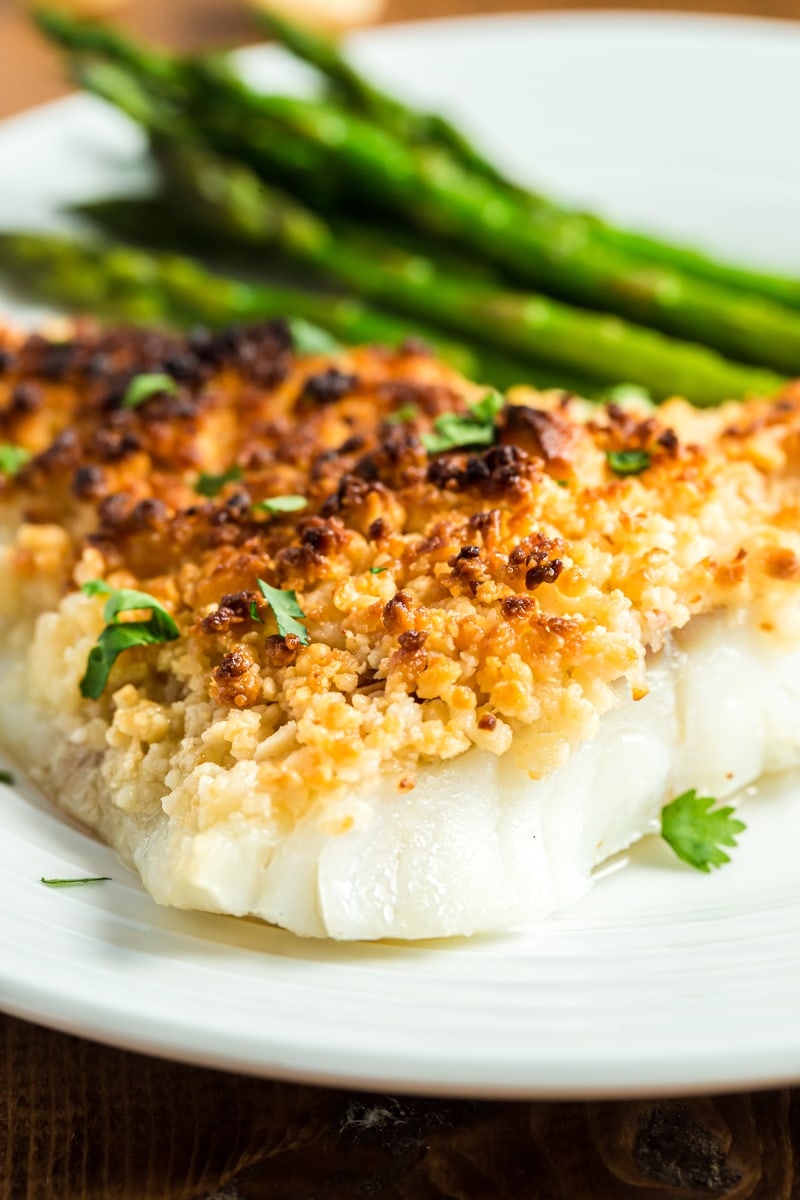 Oven baked coconut macadamia fish fillet on a white plate with green beans.