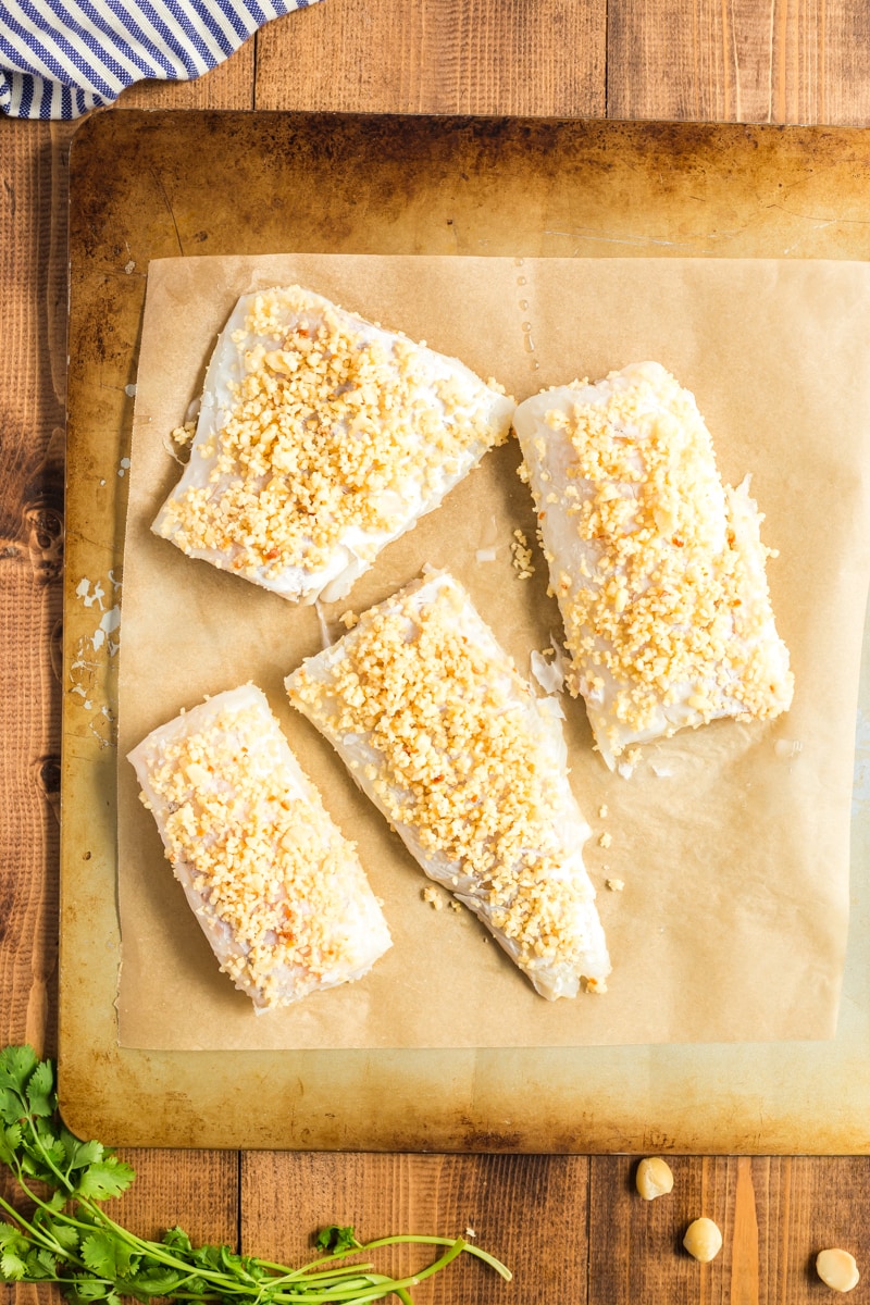 Cod fillets on the baking sheet with macadamia nuts.