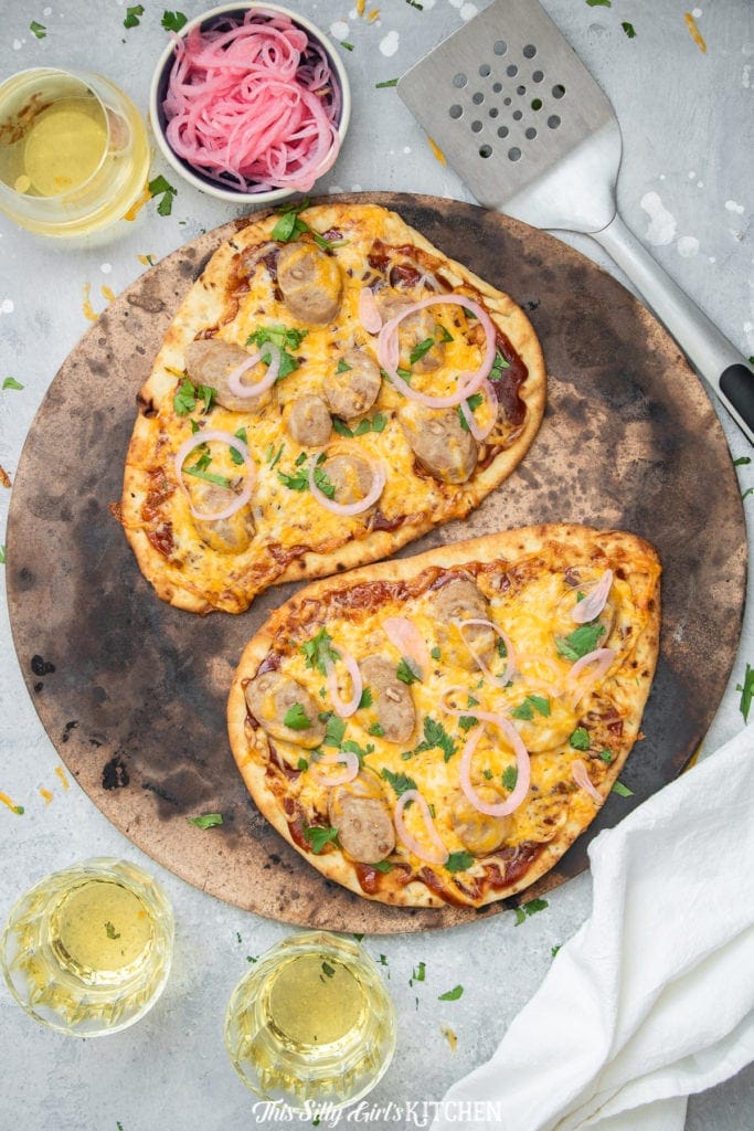 Two BBQ chicken flatbread pizzas on a pizza stone.
