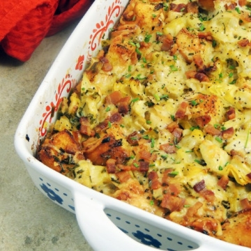 Bacon leek and artichoke bread pudding in a white casserole dish.