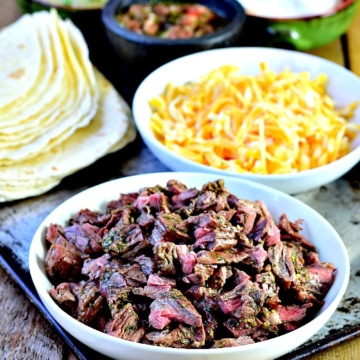 The ingredients needed for a carne asada burrito bar on a wooden table.