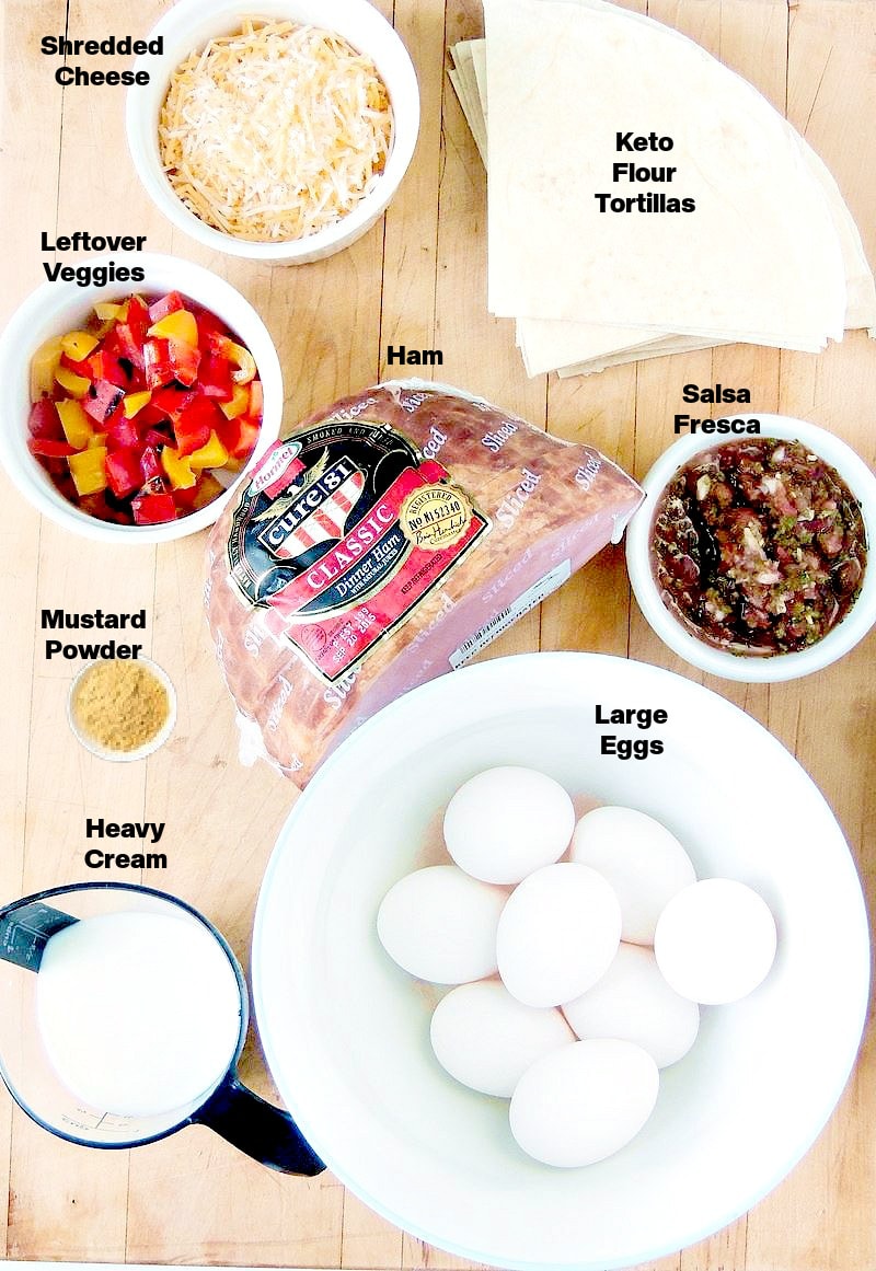 The ingredients needed to make ham and cheese breakfast burrito bites on a wooden cutting board.