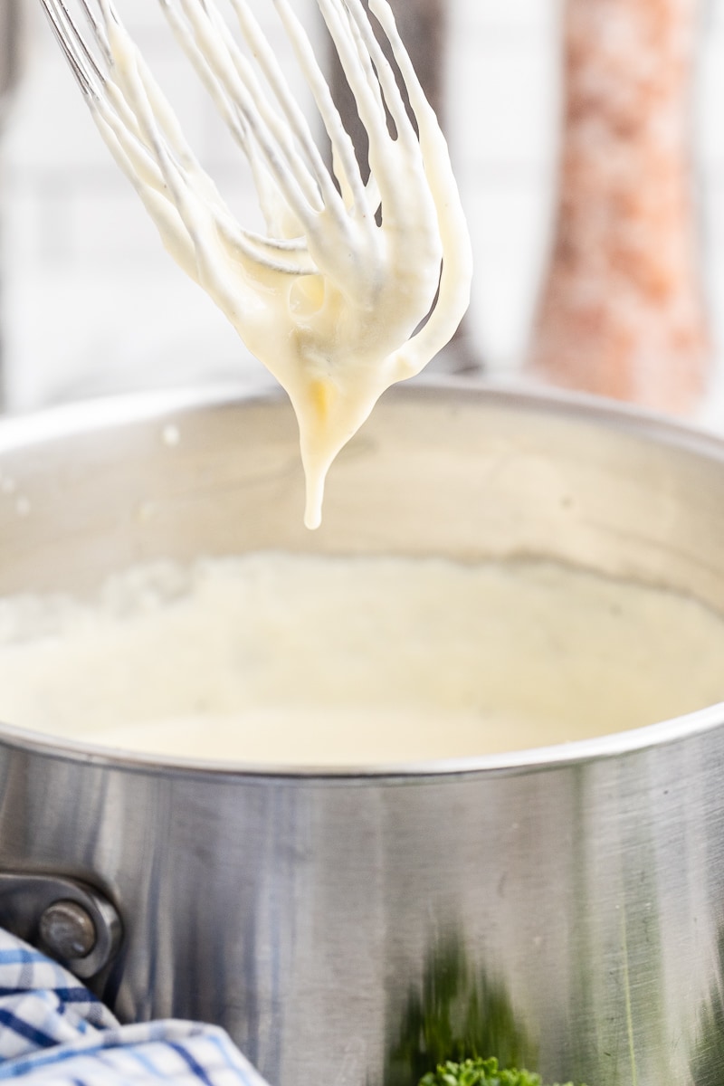 Swiss cheese sauce in a pot with a whisk.