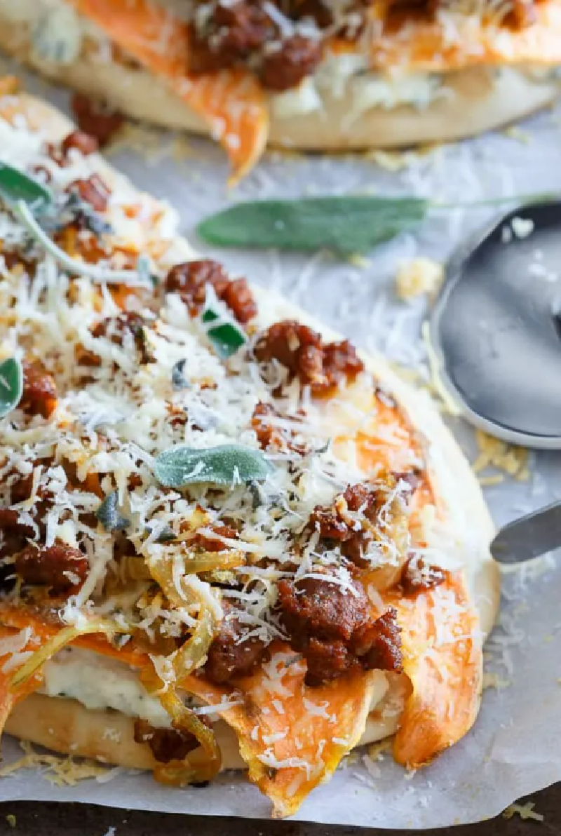 Sage chorizo sweet potato naan pizza on a parchment lined baking sheet.