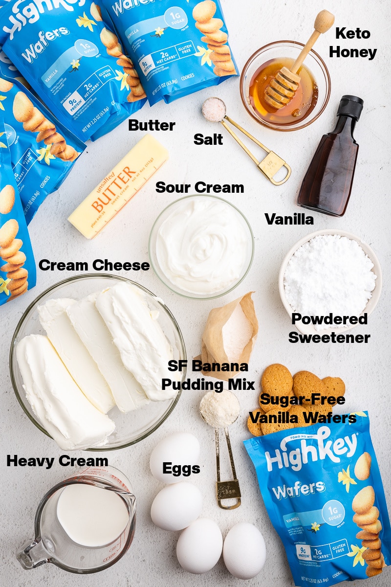 Overhead view of the ingredients needed to make Keto Banana Pudding Cheesecake on a white marble counter.