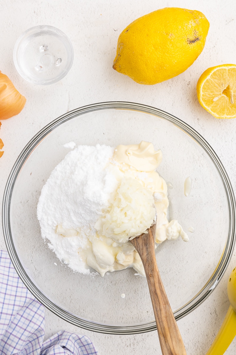 Overhead view of glass mixing bowl with ingredients for Keto KFC Coleslaw sauce. Homemade buttermilk, mayo, and sweetener. Creamy and sweet mixture for the low-carb coleslaw recipe!