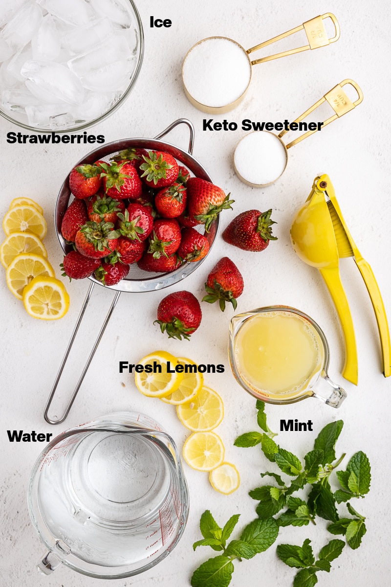 Overhead view of the ingredients needed to make Sugar-Free Strawberry Lemonade on a white marble counter.