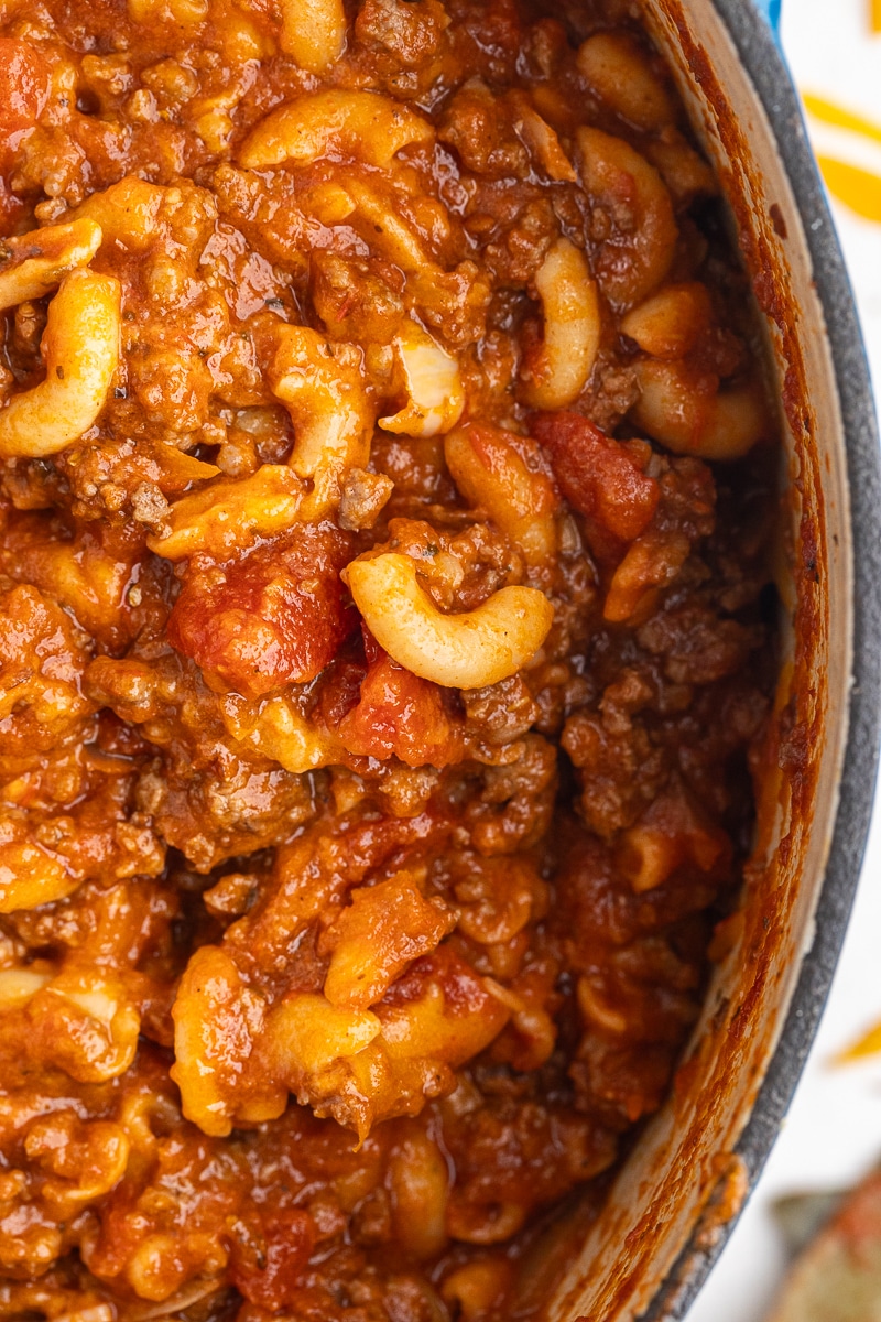 An overhead view of a Dutch oven containing a hearty and flavorful Keto Goulash (American Chop Suey). The goulash is perfectly cooked, showcasing the rich sauce, tender diced tomatoes, and plump low carb pasta. The inviting presentation highlights the delicious textures and flavors of this comforting dish.