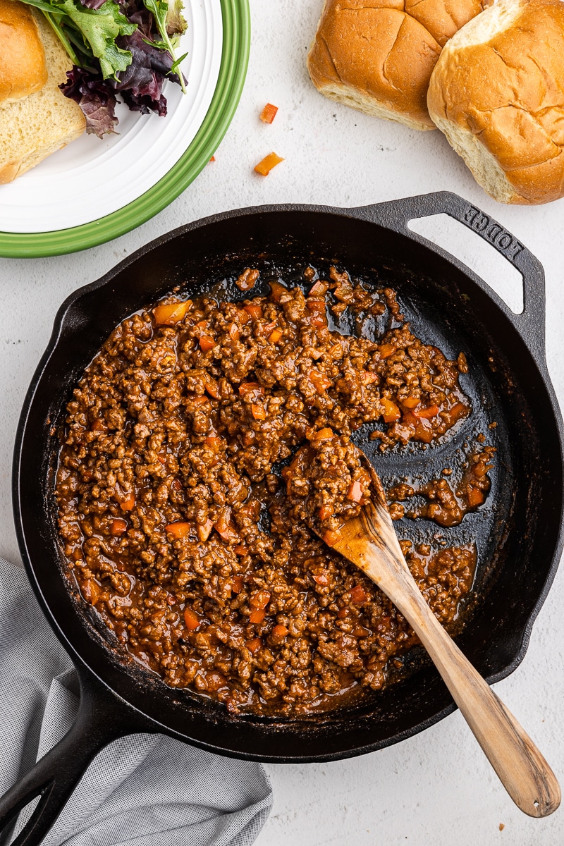 Final Step of Keto Sloppy Joes Recipe - Overhead view of the finished sloppy joe filling in a cast iron skillet. Rich and deep red color with vibrant pops of orange from the cooked bell pepper.